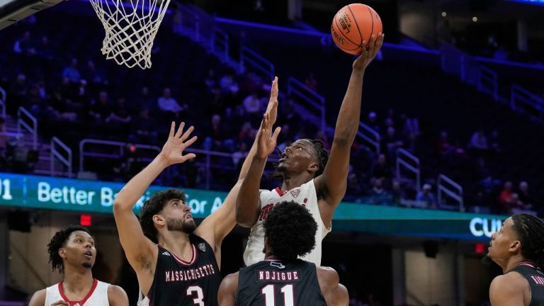Miami (Ohio) forward Antwone Woolfolk shoots over Massachusetts' Leonardo Bettiol (3) and Jayden Ndjigue (11) in the first half of an NCAA college game in the quarterfinals of the Mid-American Conference tournament, Thursday, March 12, 2026, in Cleveland. (AP Photo/Sue Ogrocki)