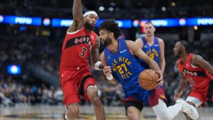 Denver Nuggets guard Jamal Murray, right, drives past Toronto Raptors forward Brandon Ingram in the first half of an NBA basketball game Friday, March 20, 2026, in Denver. (AP Photo/David Zalubowski)