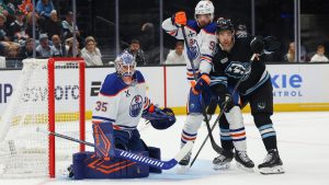 Utah Mammoth right wing Dylan Guenther (11) watches the puck against Edmonton Oilers goalie Tristan Jarry (35) and defenseman Jake Walman (96) during the second period of an NHL hockey game, Tuesday, March 24, 2026, in Salt Lake City. (Melissa Majchrzak/AP)