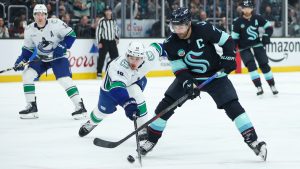Vancouver Canucks left wing Drew O'Connor (18) and Seattle Kraken right wing Jordan Eberle (7) battle for a loose puck in the first period during an NHL hockey game Saturday, Feb. 28, 2026, in Seattle. (Kevin Ng/AP)