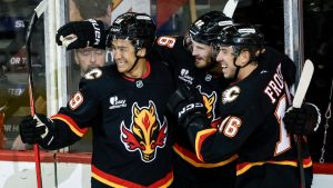 Calgary Flames' Joel Farabee, centre, celebrates his goal with teammates Zayne Parekh, left, and Morgan Frost during second period NHL hockey action against the Carolina Hurricanes in Calgary on Saturday, March 7, 2026. (Jeff McIntosh/THE CANADIAN PRESS)