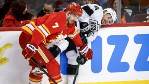Los Angeles Kings' Adrian Kempe, right, is checked by Calgary Flames' Kevin Bahl during second period NHL hockey action in Calgary on Tuesday, March 24, 2026. (Jeff McIntosh/THE CANADIAN PRESS)