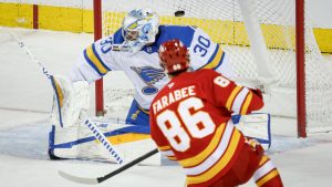 St. Louis Blues goalie Joel Hofer, left, lets in a goal from Calgary Flames' Joel Farabee that was later called back during second period NHL hockey action in Calgary on Wednesday, March 18, 2026. (Jeff McIntosh/CP)