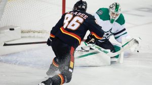 Dallas Stars goalie Casey DeSmith, right, looks on as Calgary Flames' Joel Farabee misses the net during first period NHL action in Calgary on Tuesday, March 3, 2026. (THE CANADIAN PRESS/Jeff McIntosh)