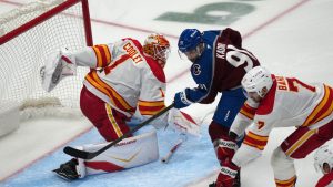 Colorado Avalanche centre Nazem Kadri drives past Calgary Flames defenseman Kevin Bahl, right, to put a shot on goaltender Devin Cooley in the third period of an NHL hockey game Monday, March 30, 2026, in Denver. (David Zalubowski/AP)