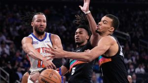 New York Knicks' Jalen Brunson, left, passes around San Antonio Spurs' Victor Wembanyama, right, and Stephon Castle during the first half of an NBA basketball game Sunday, March 1, 2026, in New York. (Seth Wenig/AP)