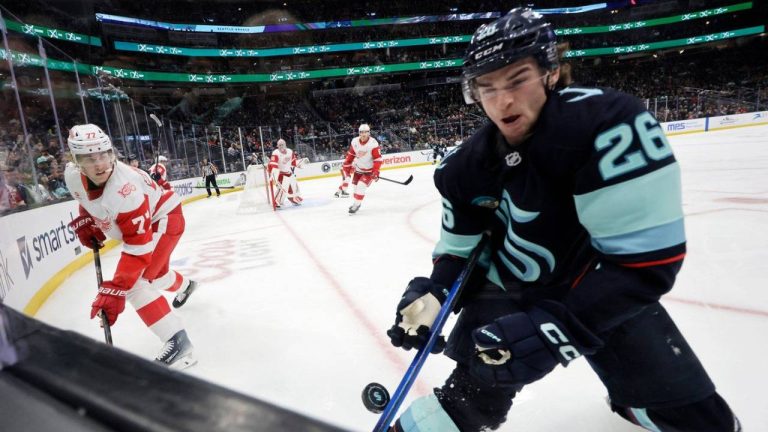 Seattle Kraken center Ryan Winterton (26) reaches for a puck at the glass with Detroit Red Wings defenseman Simon Edvinsson (77), left, during the third period of an NHL hockey game Dec. 6, 2025, in Seattle. (John Froschauer/AP)