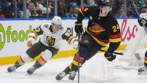 Vancouver Canucks' Zeev Buium (24) skates with the puck away from Vegas Golden Knights' Mitch Marner (93) during the second period of an NHL hockey game, in Vancouver, on Tuesday, April 7, 2026. (Darryl Dyck/CP)