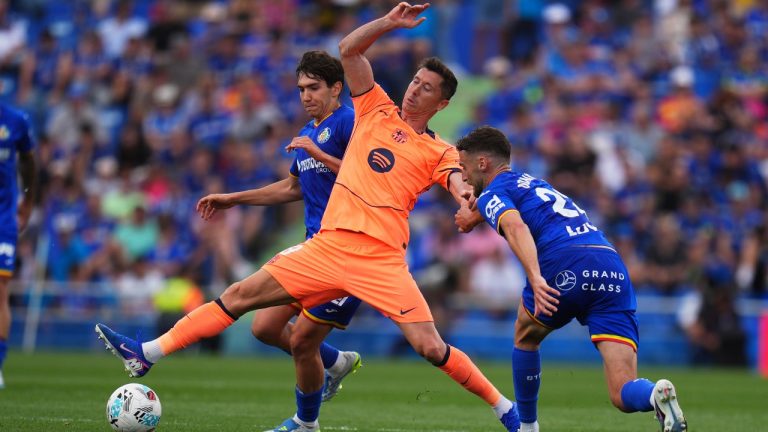 Barcelona's Robert Lewandowski, center, tries to reach the ball past Getafe's Mario Martin, left, during the Spanish La Liga soccer match between Getafe and Barcelona in Getafe, Spain, Saturday, April 25, 2026. (AP Photo/Manu Fernandez)