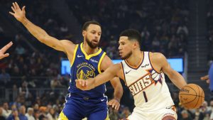 Phoenix Suns guard Devin Booker (1) drives to the basket against Golden State Warriors guard Stephen Curry (30) during the first half of an NBA basketball game in San Francisco, Tuesday, Nov. 4, 2025. (AP Photo/Jed Jacobsohn)