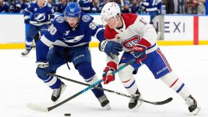 Montréal Canadiens right wing Cole Caufield (13) and Tampa Bay Lightning defenseman J.J. Moser (90) battle for control of the puck during the first period of an NHL hockey game Sunday, Dec. 28, 2025, in Tampa, Fla. (Chris O'Meara/AP)