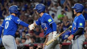 Toronto Blue Jays'Andres Gimenez (0) celebrates his run scored against the Arizona Diamondbacks with Blue Jays' Ernie Clement (22) as Blue Jays' Kazuma Okamoto, right, of Japan, looks on during the first inning of a baseball game, Sunday, April 19, 2026, in Phoenix. (Ross D. Franklin/AP)