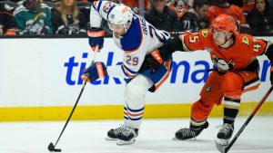 Edmonton Oilers center Leon Draisaitl, left, controls the puck as Anaheim Ducks right wing Beckett Sennecke defends during the second period of Game 4 in the first round of an NHL hockey Stanley Cup playoff series Sunday, April 26, 2026, in Anaheim, Calif. (AP Photo/Kyusung Gong)