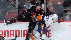 Ottawa Senators' Thomas Chabot collides with New York Islanders' Emil Heineman along the boards during first period NHL action in Ottawa, Thursday, March 19, 2026. (THE CANADIAN PRESS/Adrian Wyld)
