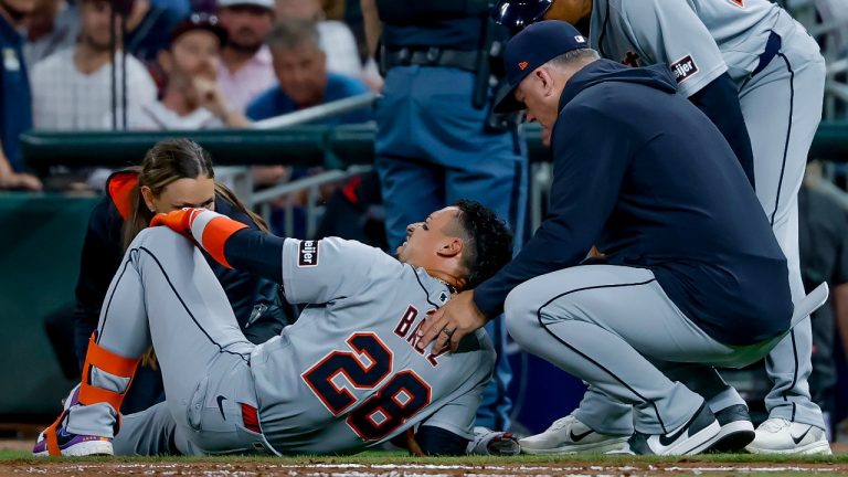 Detroit Tigers' Javier Baez (28) is examined by Tigers manager A.J. Hinch, right, and a team trainer after injuring his right leg running to first base on a ground ball against the Atlanta Braves during the fifth inning of a baseball game, Tuesday, April 28, 2026, in Atlanta. (Erik S. Lesser/AP)