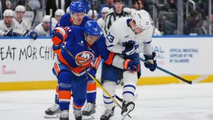 New York Islanders' Brayden Schenn (10) and Bo Horvat (14) fight for control of the puck with Toronto Maple Leafs' Matthew Knies (23) during the first period of an NHL hockey game Thursday, April 9, 2026, in Elmont, N.Y. (Frank Franklin II/AP)