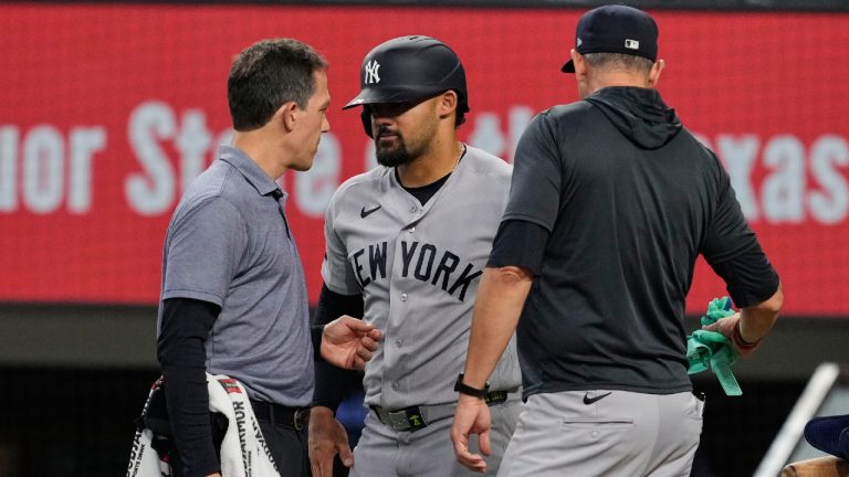 New York Yankees' Jasson Dominguez, centre, talks with a team trainer as manager Aaron Boone, right, looks on after Dominguez was hit by a pitch in the fourth inning of a baseball game against the Texas Rangers Wednesday, April 29, 2026, in Arlington, Texas. (Tony Gutierrez/AP)