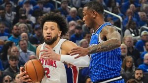 Detroit Pistons guard Cade Cunningham, left, moves past Orlando Magic forward Jamal Cain during the first half in Game 4 of a first-round NBA basketball playoff series, Monday, April 27, 2026, in Orlando, Fla. (AP Photo/John Raoux)