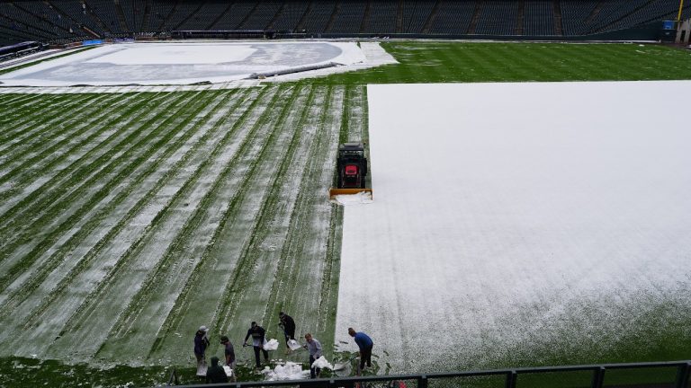 Grounds crew members toil to clear the outfield of Coors Field after a spring storm blanketed the intermountain West with a light covering of snow before the Colorado Rockies host the Los Angeles Dodgers in a baseball game Friday, April 17, 2026, in Denver. (AP Photo/David Zalubowski)