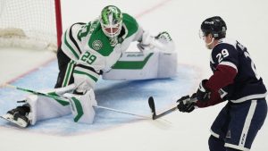 Colorado Avalanche center Nathan MacKinnon, right, has his shot stopped by Dallas Stars goaltender Jake Oettinger to seal a victory for the Stars during a shootout in an NHL hockey game Wednesday, March 18, 2026, in Denver. (AP Photo/David Zalubowski)