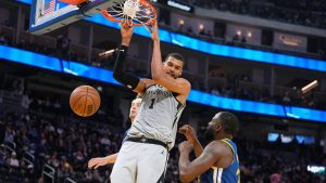 San Antonio Spurs forward Victor Wembanyama (1) dunks against Golden State Warriors forward Draymond Green, right, during the first half of an NBA basketball game in San Francisco, Wednesday, April 1, 2026. (AP Photo/Tony Avelar)