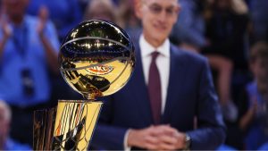 NBA commissioner Adam Silver stands behind the Larry O'Brien trophy during a ceremony before an NBA basketball game between the Houston Rockets and Oklahoma City Thunder, Tuesday, Oct. 21, 2025, in Oklahoma City. (AP Photo/Nate Billings)