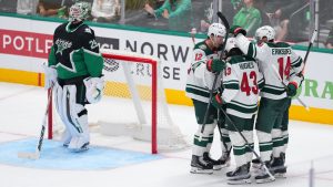 Dallas Stars goaltender Jake Oettinger, left, looks on as Minnesota Wild's Matt Boldy (12) and Quinn Hughes (43) celebrate a goal by Joel Eriksson Ek (14) during the third period in Game 1 of a first-round NHL Stanley Cup playoffs hockey series, Saturday, April 18, 2026, in Dallas, Texas. (AP Photo/Julio Cortez)