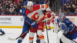 Calgary Flames centre Tyson Gross, centre, avoids a shot while jostling for position in front of the net between Colorado Avalanche defenceman Sam Malinski, left, and goaltender MacKenzie Blackwood, right, in the second period of an NHL hockey game Thursday, April 9, 2026, in Denver. (David Zalubowski/AP)
