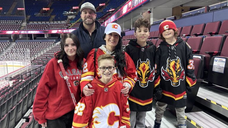 Kade Heisler, centre, smiles for a photo after meeting his idol, Calgary Flames goalie Dustin Wolf. (Eric Francis/Sportsnet)