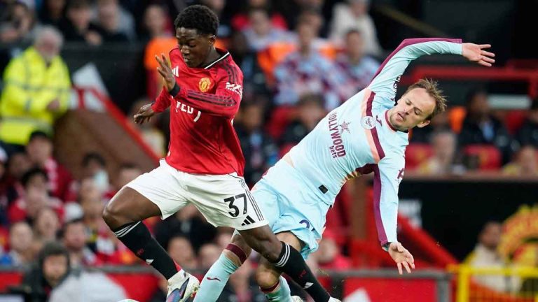 Manchester United's Kobbie Mainoo, left, and Brentford's Mikkel Damsgaard fight for the ball during the Premier League soccer match between Manchester United and Brentford. (Dave Thompson/AP)