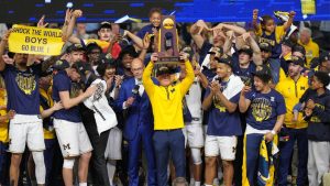 Michigan head coach Dusty May hold up the trophy as he celebrates after defeating UConn in the NCAA college basketball tournament national championship game at the Final Four, Monday, April 6, 2026, in Indianapolis. (AJ Mast/AP)