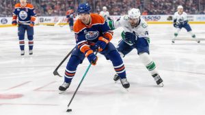 Vancouver Canucks' Jake DeBrusk (74) and Edmonton Oilers' Evan Bouchard (2) battle for the puck during first period NHL action, in Edmonton on Thursday April 16, 2026. (Jason Franson/CP)