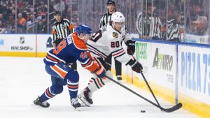 Chicago Blackhawks Ryan Greene (20) and Edmonton Oilers' Ty Emberson (49) battle for the puck during first period NHL action, in Edmonton on Thursday April 2, 2026. (Jason Franson/CP)