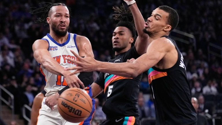 New York Knicks' Jalen Brunson, left, passes around San Antonio Spurs' Victor Wembanyama, right, and Stephon Castle during the first half of an NBA basketball game Sunday, March 1, 2026, in New York. (Seth Wenig/AP)