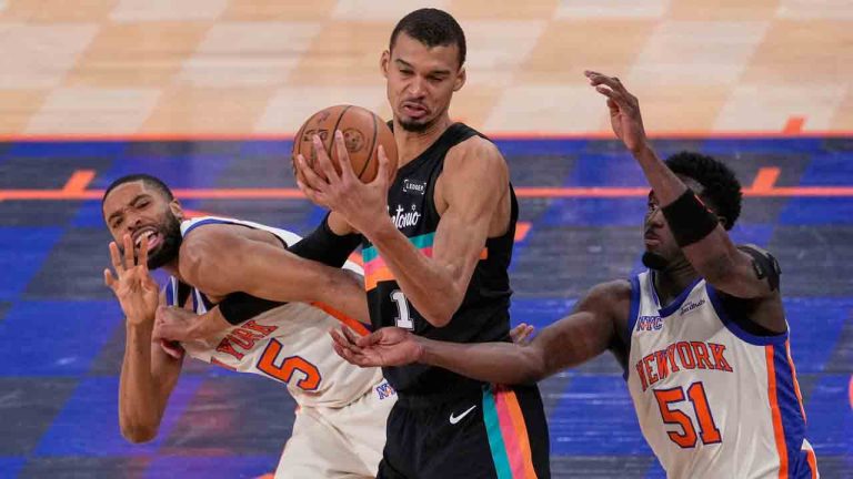 New York Knicks' Mikal Bridges, left, fouls San Antonio Spurs' Victor Wembanyama, center, while Bridges and Mohamed Diawara (51) try to get to the ball during the second half of an NBA basketball game Sunday, March 1, 2026, in New York. (Seth Wenig/AP)
