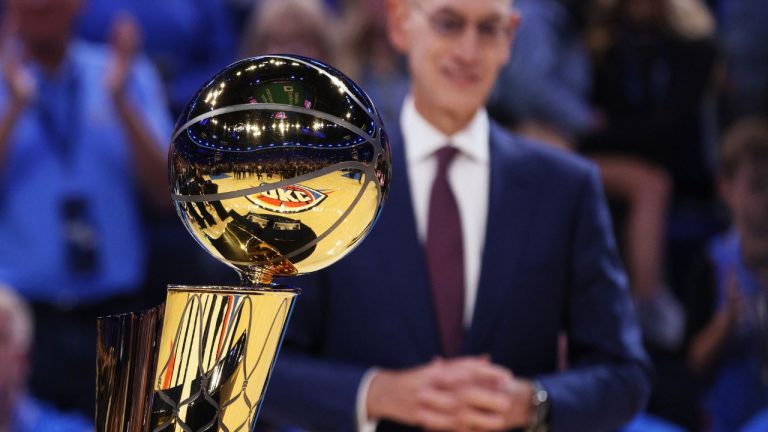 NBA commissioner Adam Silver stands behind the Larry O'Brien trophy during a ceremony before an NBA basketball game between the Houston Rockets and Oklahoma City Thunder, Tuesday, Oct. 21, 2025, in Oklahoma City. (Nate Billings/AP)