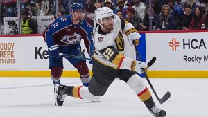 Vegas Golden Knights defenceman Dylan Coghlan, front, shoots the puck for a goal after driving past Colorado Avalanche centre Brock Nelson during the second period in Game 1 of the Western Conference Final NHL hockey Stanley Cup playoff series Wednesday, May 20, 2026, in Denver. (David Zalubowski/AP)
