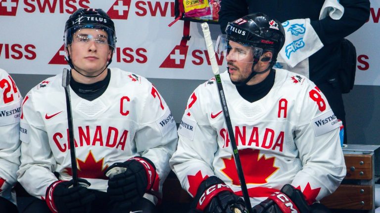 Canada's Sidney Crosby, right, speaks with Macklin Celebrini while sitting on the bench during a Group B preliminary round game between Canada and Slovenia at the men's ice hockey world championship in Fribourg, Switzerland, Friday May 22, 2026. (Salvatore Di Nolfi/Keystone via AP)