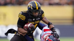 Hamilton Tiger-Cats wide receiver Isaiah Wooden drives the ball through Montreal Alouettes punter Joseph Zema during first half CFL eastern final football action in Hamilton, Ont., Saturday, Nov. 8, 2025. (Frank Gunn/CP)