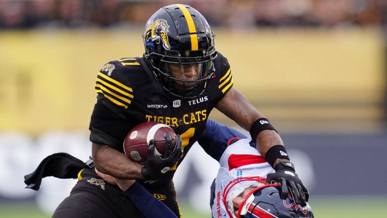 Hamilton Tiger-Cats wide receiver Isaiah Wooden drives the ball through Montreal Alouettes punter Joseph Zema during first half CFL eastern final football action in Hamilton, Ont., Saturday, Nov. 8, 2025. (Frank Gunn/CP)
