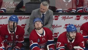 Canadiens captain Nick Suzuki (14) alongside forwards Cole Caufield (13) and Kirby Dach (77) watch the final minutes tick down against the Carolina Hurricanes in front of head coach Martin St. Louis in Montreal on Wednesday, May 27, 2026. (Christinne Muschi/CP)