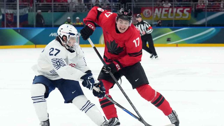 Macklin Celebrini (17) of Team Canada and Jules Boscq (27) of Team France battle for the puck during third period Olympic hockey action at the 2026 Milan Cortina Winter Olympics. (Nathan Denette/THE CANADIAN PRESS)