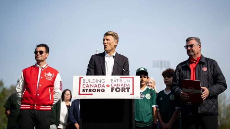 Minister of Housing and Infrastructure Gregor Robertson, centre, speaks while flanked by Secretary of State for Sport Adam van Koeverden, left, and Canada Soccer President Peter Augruso during a news conference in Vancouver, on Friday, May 1, 2026. (Ethan Cairns/CP)