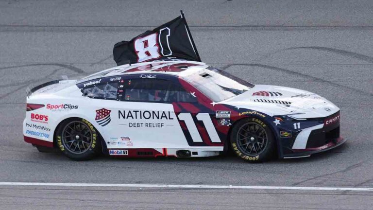 Denny Hamlin celebrates winning while honoring Kyle Busch with a flag after a NASCAR Cup Series auto race at Michigan International Speedway in Brooklyn, Mich., Sunday, June 7, 2026. (Paul Sancya/AP)
