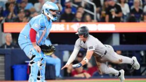 New York Yankees shortstop Max Schuemann (30) steals home to score in front of Toronto Blue Jays catcher Alejandro Kirk after a RBI single from teammate Anthony Volpe during second inning MLB baseball action in Toronto on Sunday June 14, 2026. (Chris Young/CP)