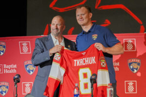Florida Panthers general manager Bill Zito, left, and Brady Tkachuk holds his jersey as the new member of the team Tuesday, June 23, 2026, in Fort Lauderdale, Fla. (AP Photo/Marta Lavandier)