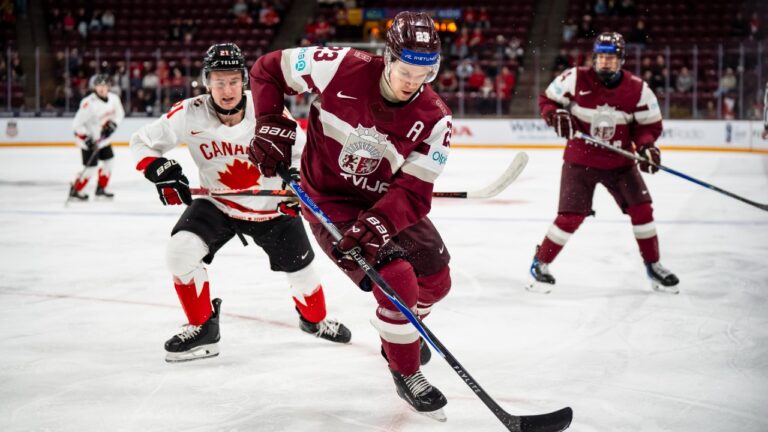 Latvia's Alberts Smits (23) defends against Canada's Cole Reschny (21) during first period IIHF World Junior Championship hockey action, in Minneapolis, Minn., on Saturday, Dec. 27, 2025. (Christopher Katsarov/CP)