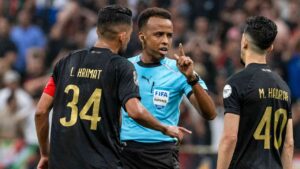 Referee Omar Artan, center, of Somalia, is confronted by players after calling a penalty kick during the CAF Champions League final soccer match between AS FAR Rabat and Mamelodi Sundowns, in Rabat, Morocco, Sunday, May 24, 2026. (Mosa'ab Elshamy/AP)