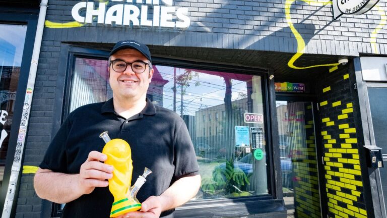 Sean Kady, owner of Cosmic Charlies, poses holding a bong resembling the FIFA World Cup trophy outside his shop on Queen Street West in Toronto on Thursday, June 4, 2026. (Arlyn McAdorey/CP)