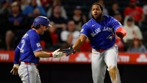 Toronto Blue Jays' Vladimir Guerrero Jr. (27) is greeted by Toronto Blue Jays' Ernie Clement (22) after scoring on a sacrifice fly from Toronto Blue Jays designated hitter Eloy Jimenez (74) during the eighth inning of a baseball game Tuesday, April 21, 2026, in Anaheim, Calif. (Caroline Brehman/AP)